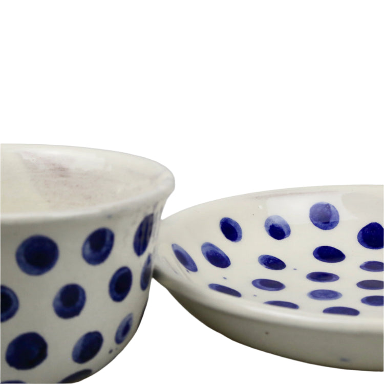 ceramic cup & saucer with blue polka dot patterns on a white background