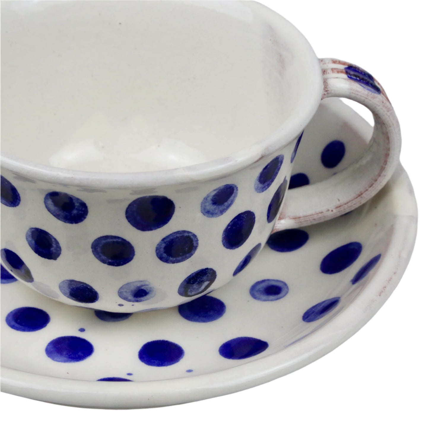 Ceramic cup and saucer with blue polka dots on a white background