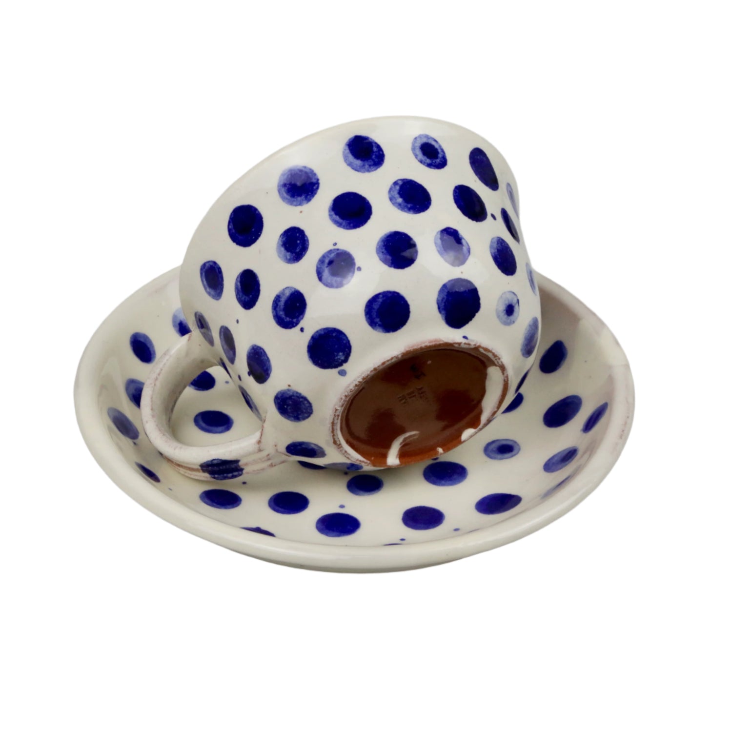Ceramic cup and saucer with blue polka dots on a white background