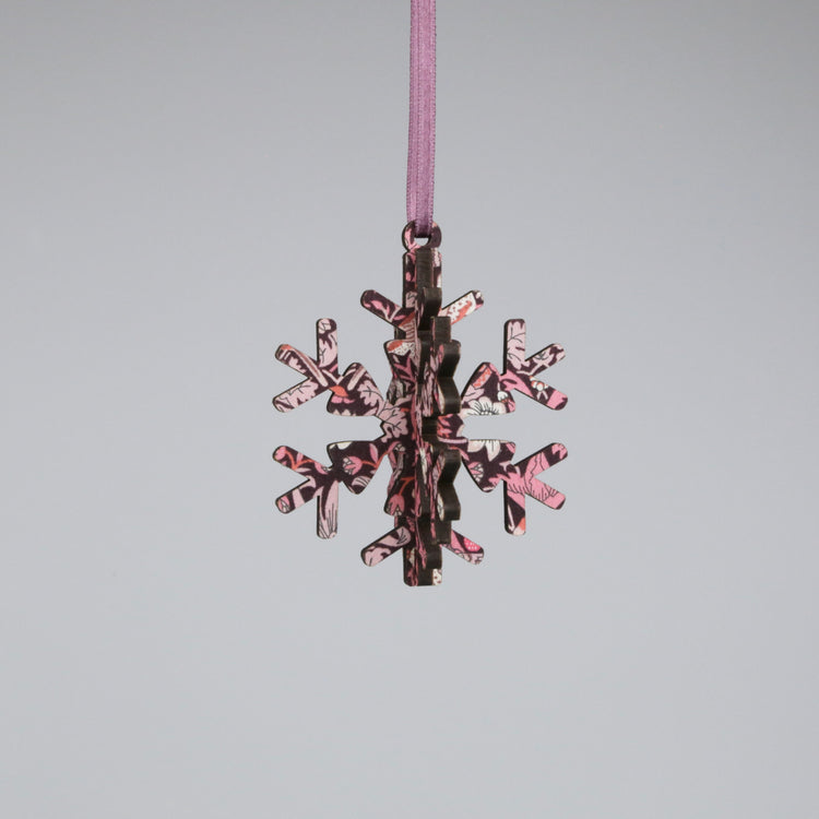 Decorative snowflake ornament with pink and brown pattern on a gray background