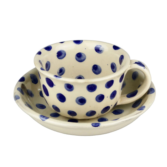 Ceramic cup and saucer set with blue polka dots on a gray background