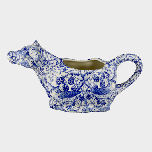 Blue and white ceramic cow-shaped creamer on a gray background