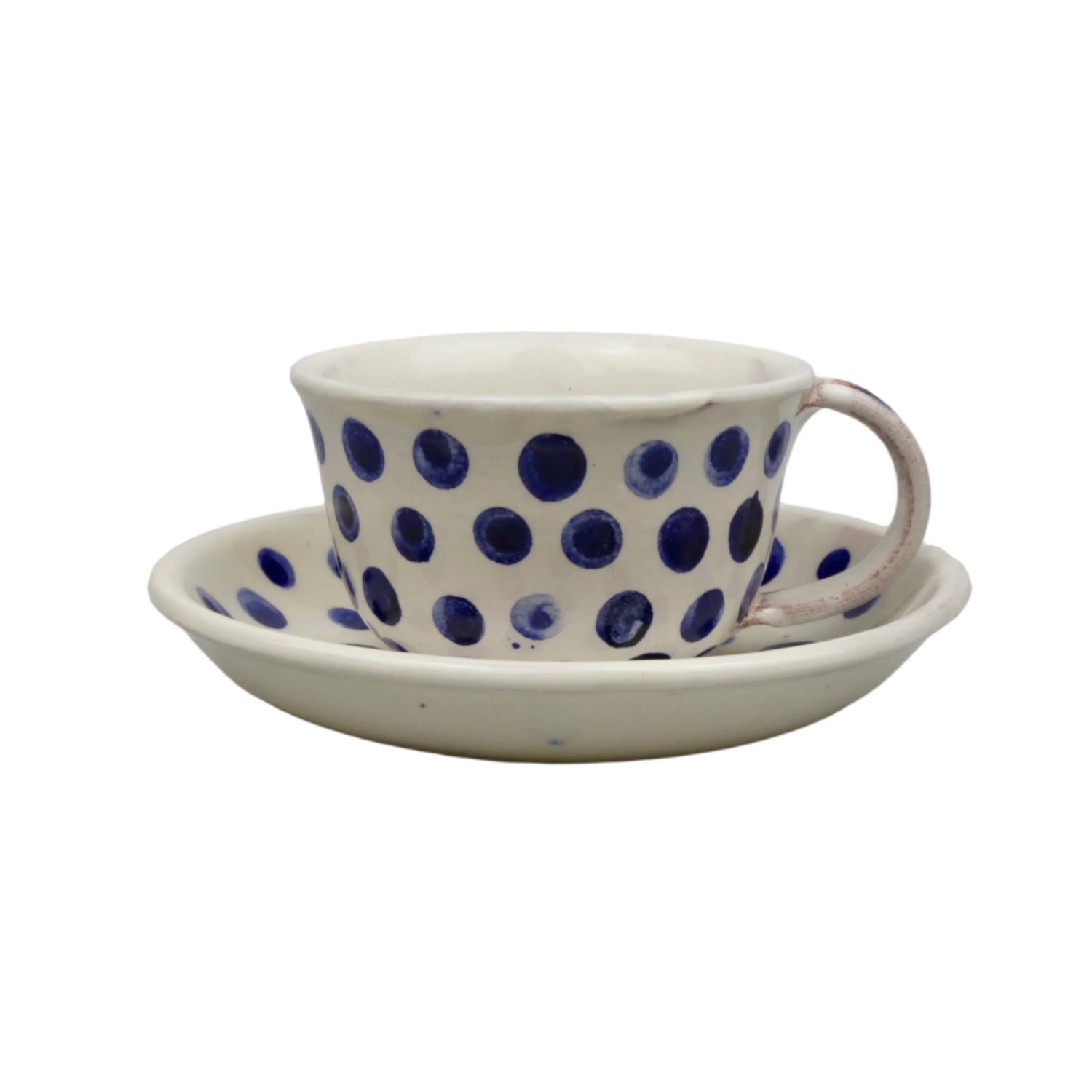 Ceramic cup with blue polka dots and matching saucer on a light gray background