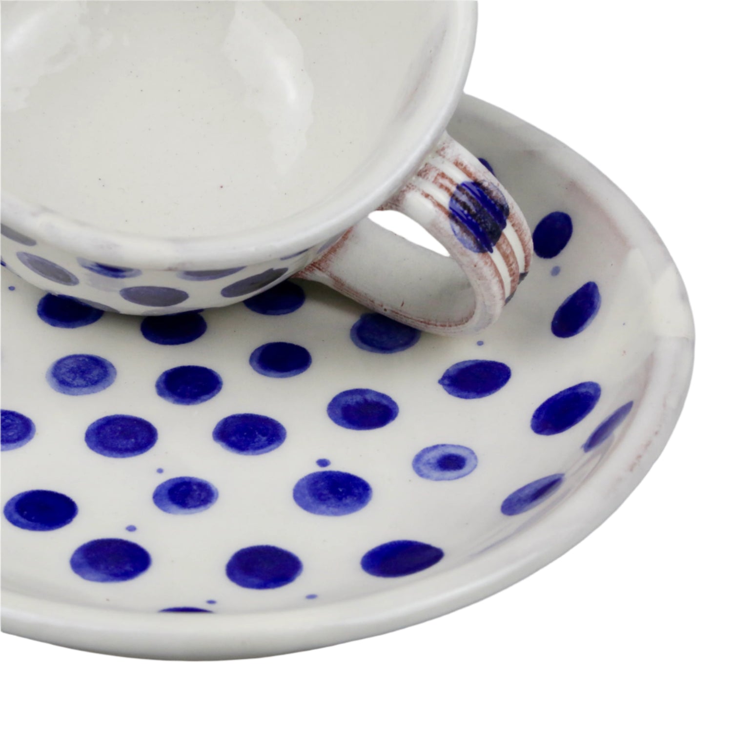 Ceramic cup and saucer with blue polka dots on a white background