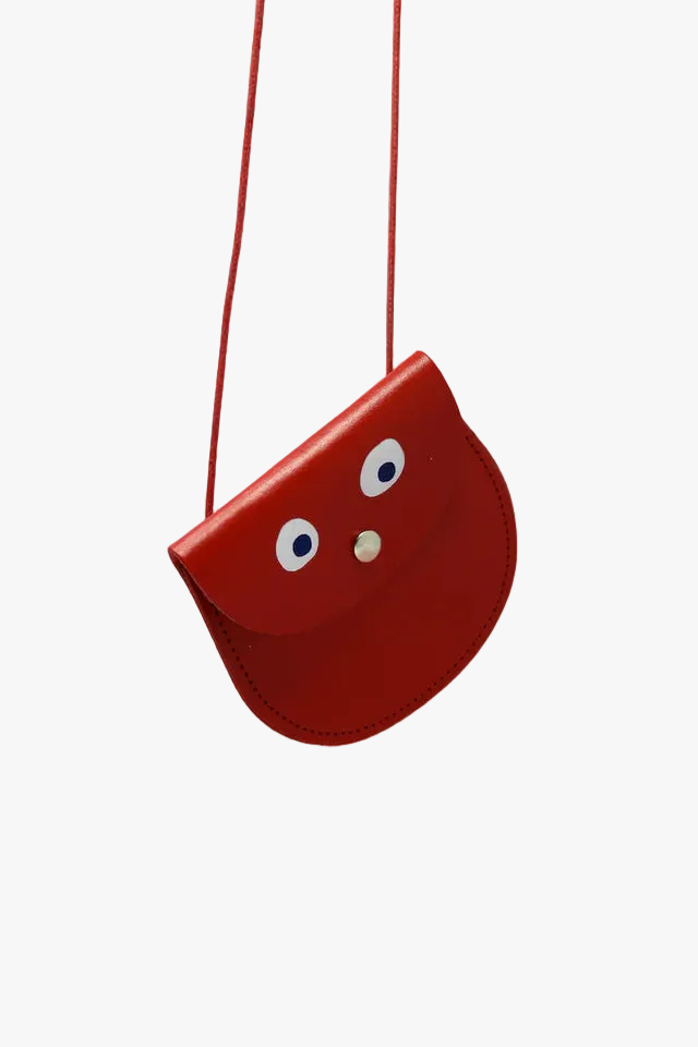 Red bag with cartoonish eyes and a nose on a pink background