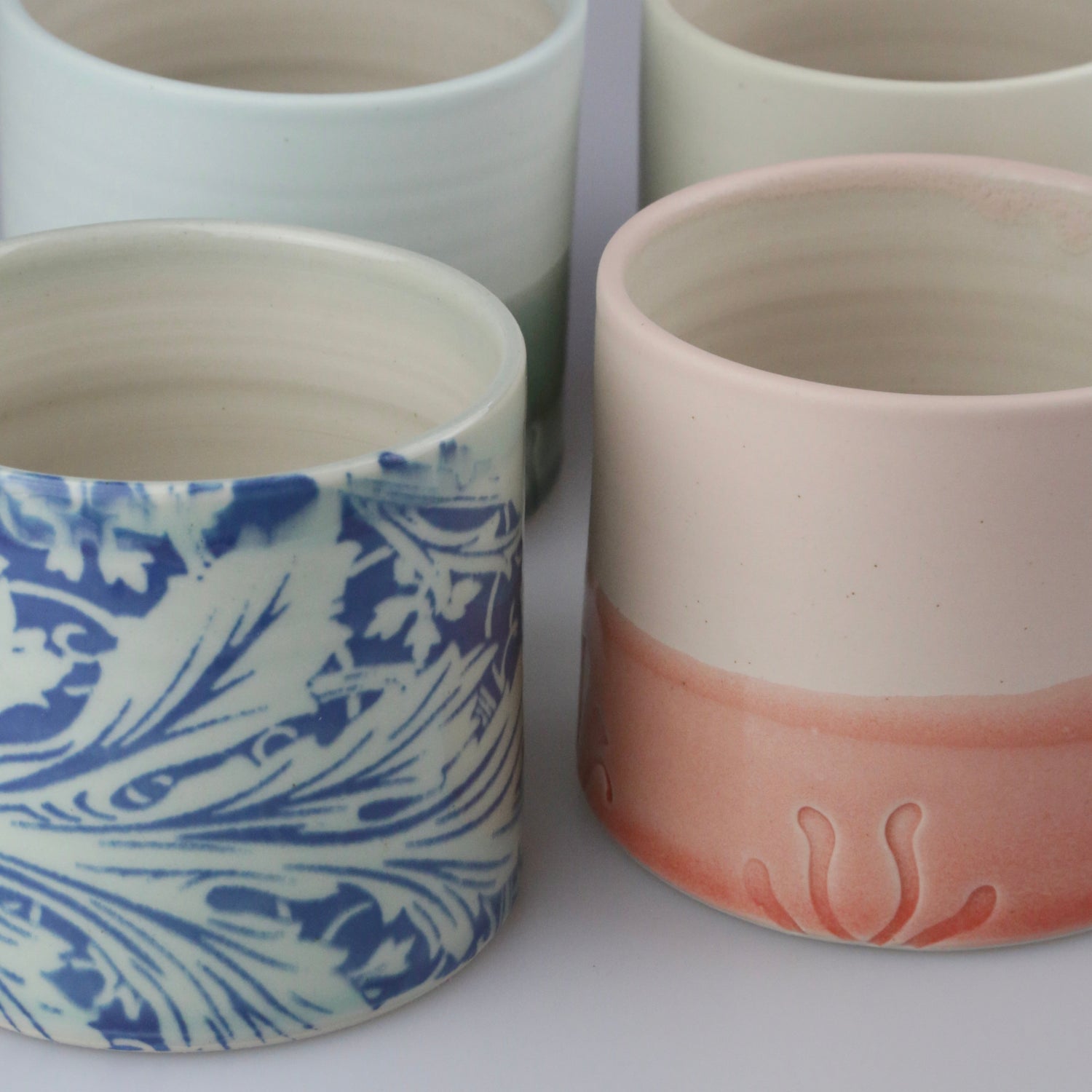 Four ceramic pots with different designs on a white background