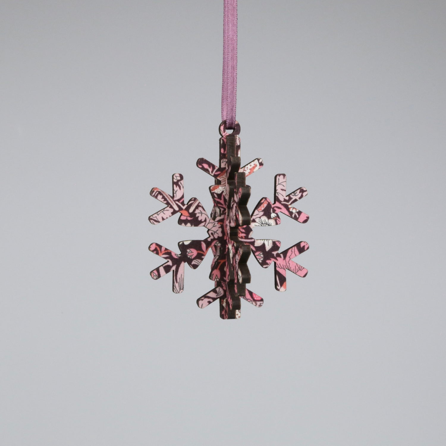 Decorative snowflake ornament with pink and brown pattern on a gray background