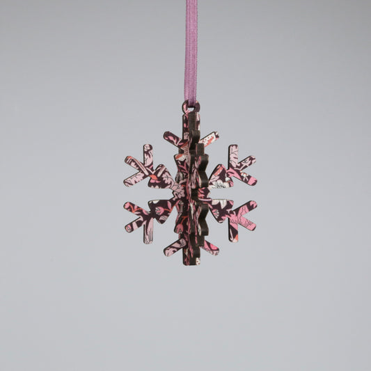 Decorative snowflake ornament with pink and brown pattern on a gray background