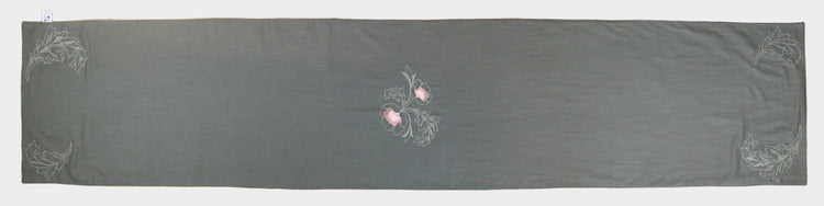 Dark gray fabric with floral embroidery on a wooden surface
