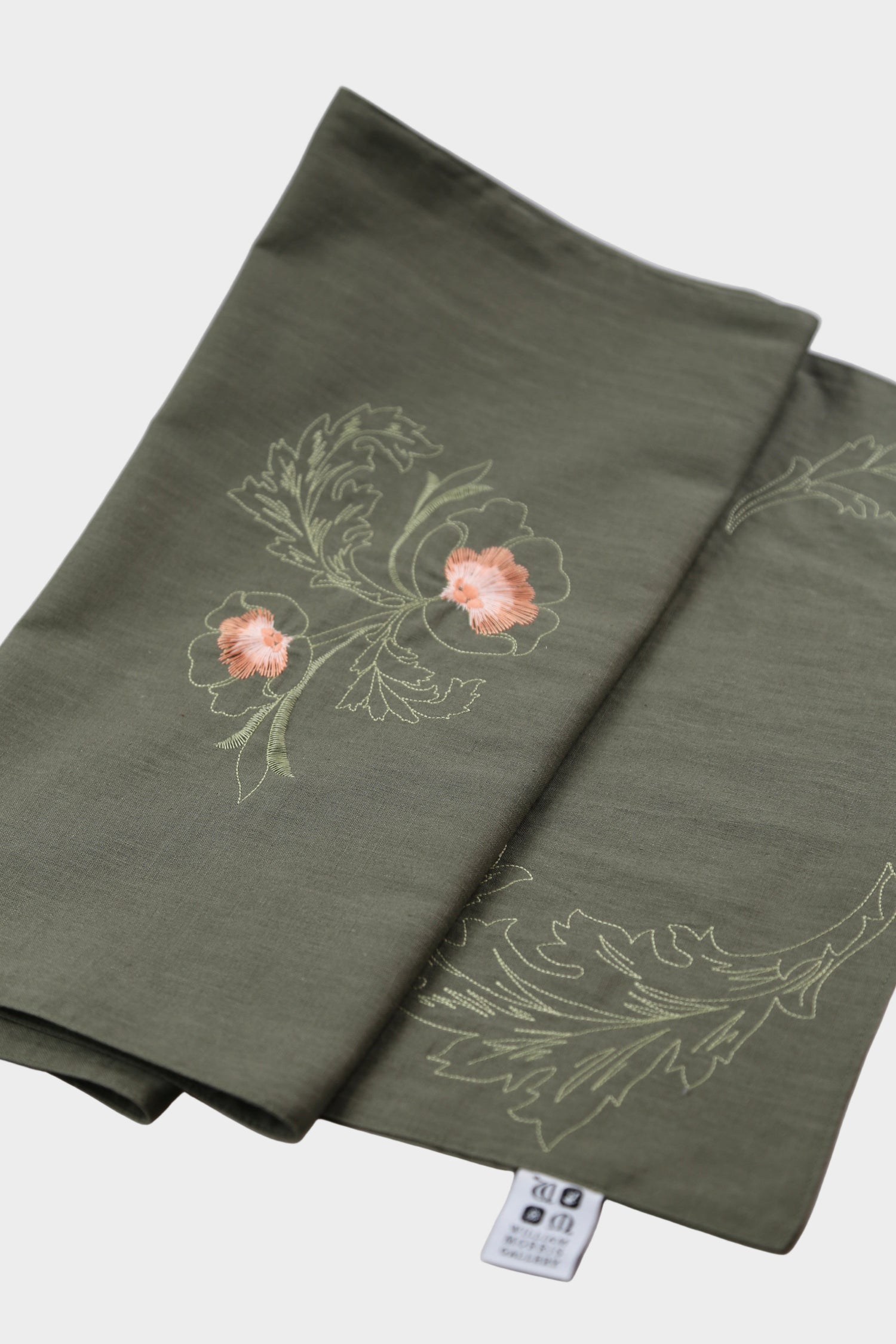 Green fabric with floral embroidery on a white surface