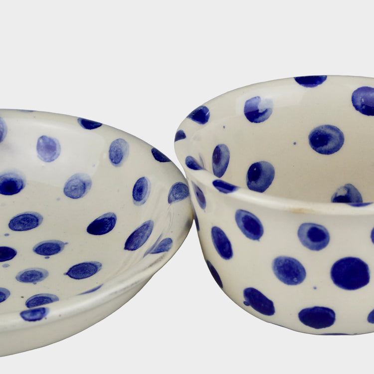 Two ceramic bowls with blue polka dot patterns on a gray background