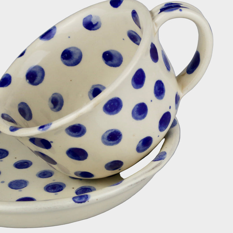 Ceramic cup and saucer with blue polka dots on a gray background