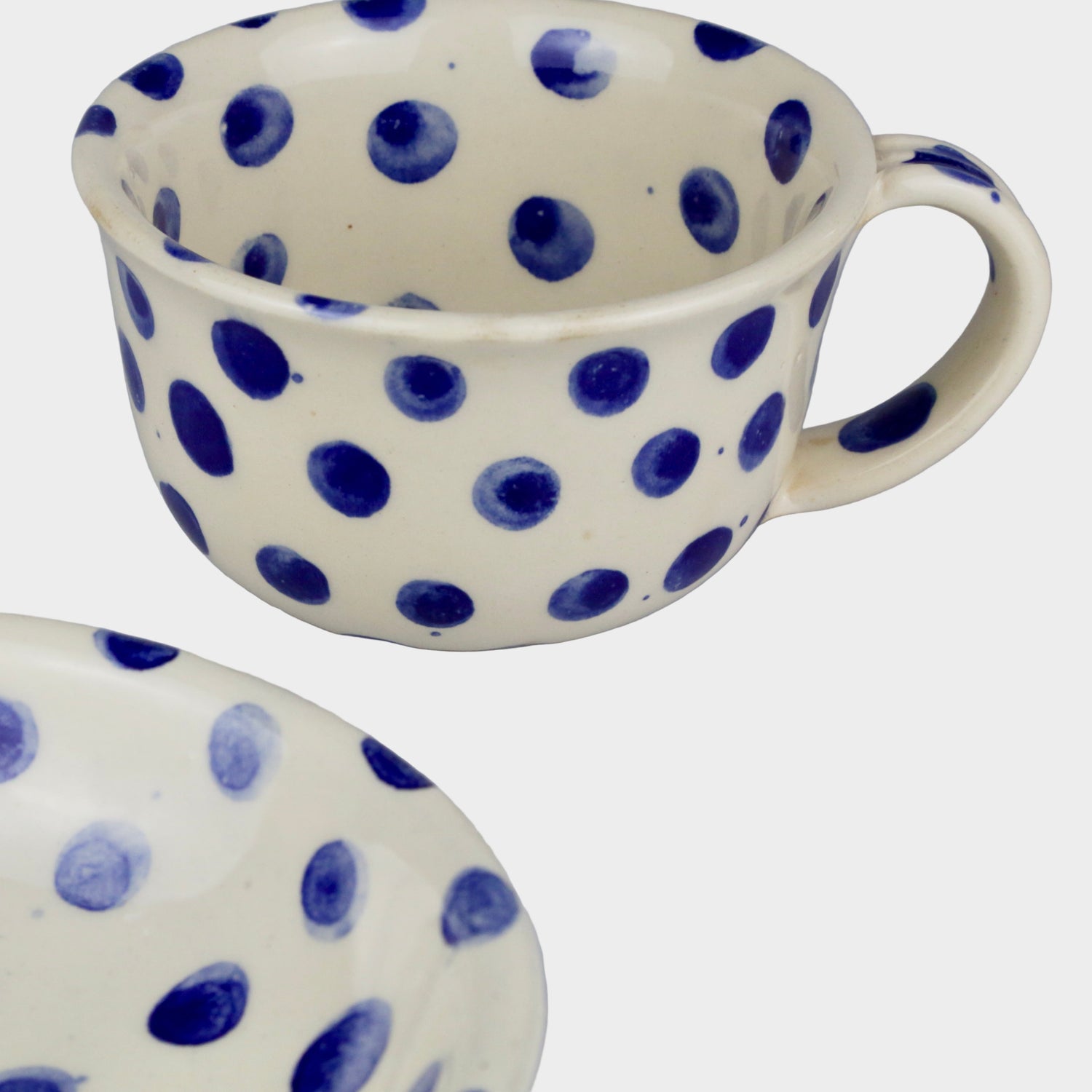 Ceramic mug and plate with blue polka dots on a gray background