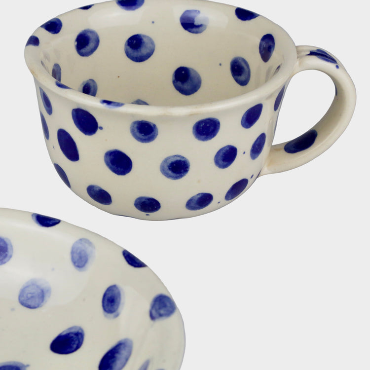 Ceramic mug and plate with blue polka dots on a gray background