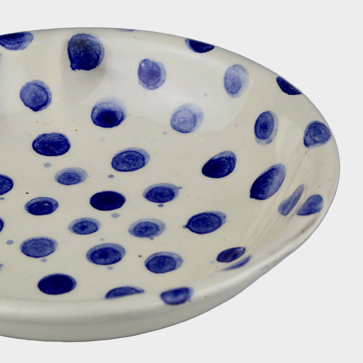 Ceramic bowl with blue polka dot pattern on a gray background