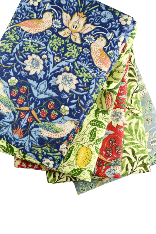 Stack of fabric swatches with floral and nature-themed patterns on a light gray background
