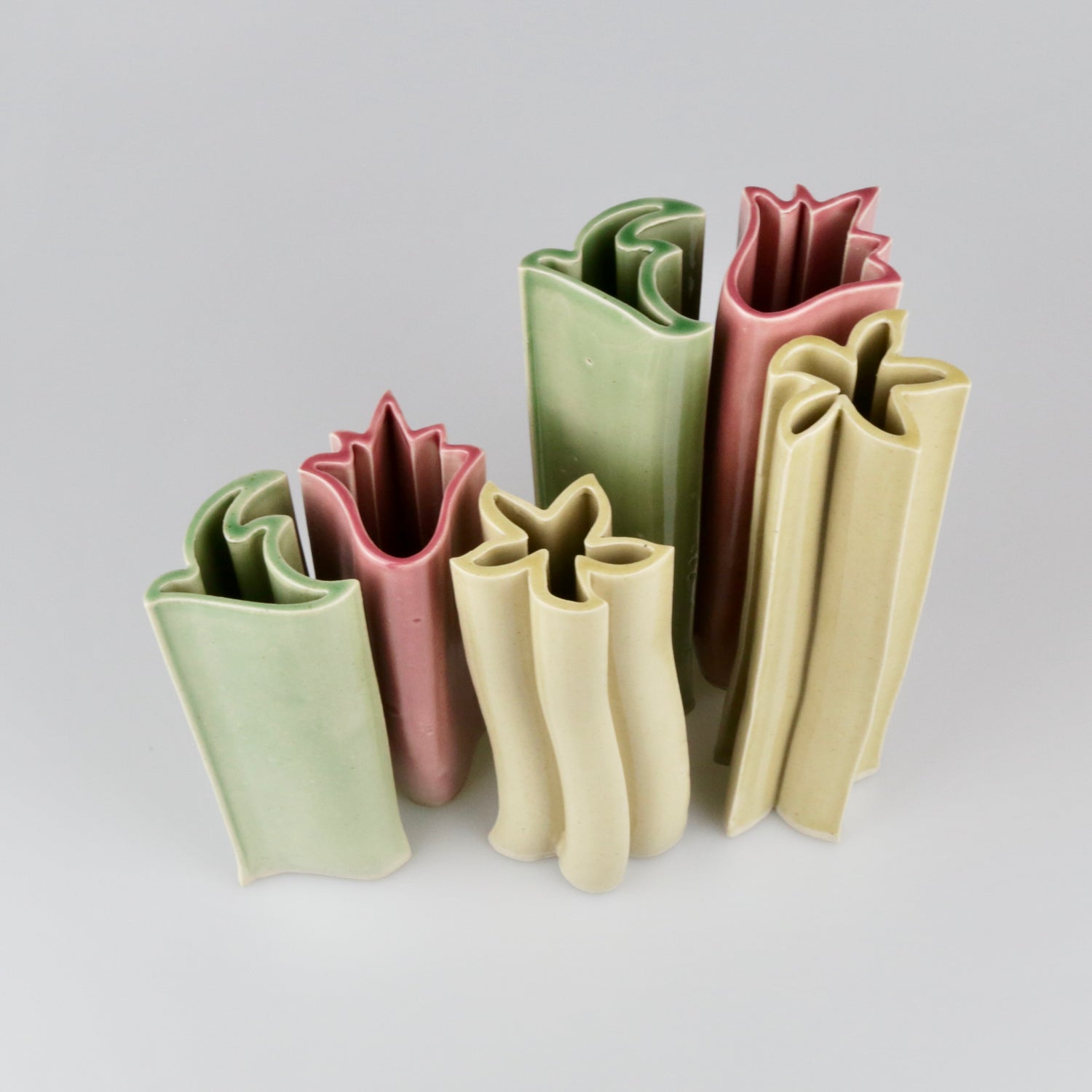 Set of five ceramic vases in different colors on a light gray background