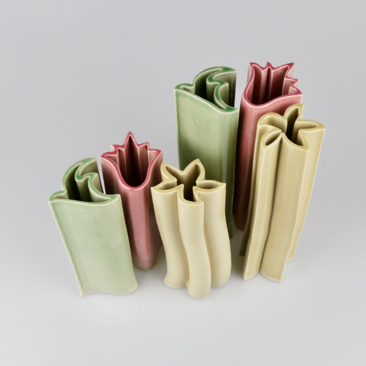 Set of five ceramic vases in different colors on a light gray background