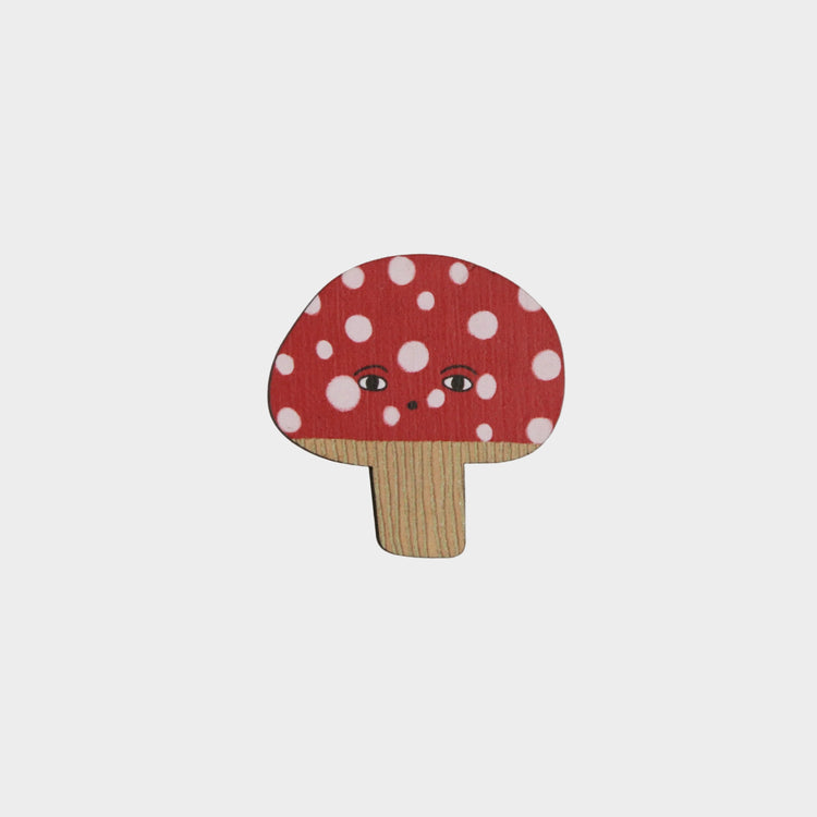 Wooden mushroom-shaped magnet with a red cap and white polka dots on a gray background
