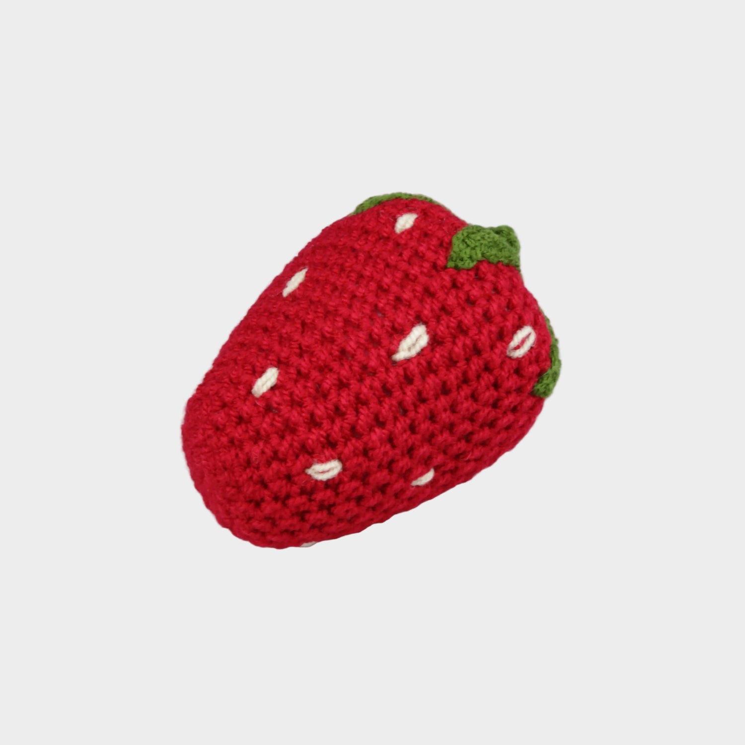 Crocheted strawberry toy on a light gray background
