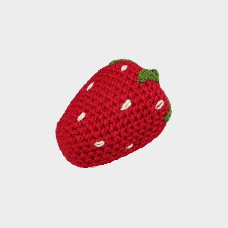 Crocheted strawberry toy on a light gray background