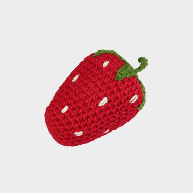 Crocheted strawberry toy on a light gray background