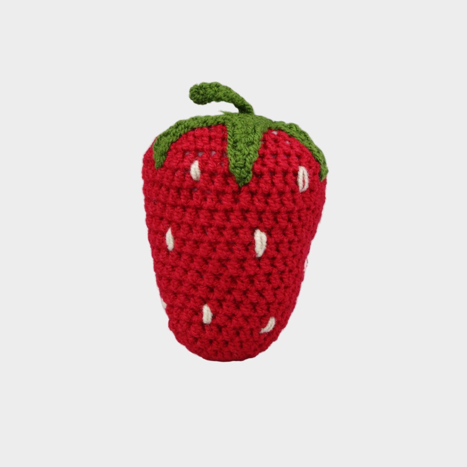 Crocheted strawberry toy on a gray background