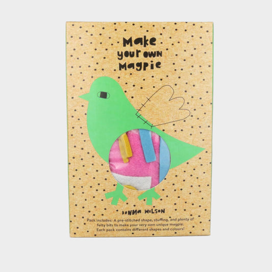 Cardboard packaging for a craft kit to make a 'magpie' with colorful bird illustration on a beige background.