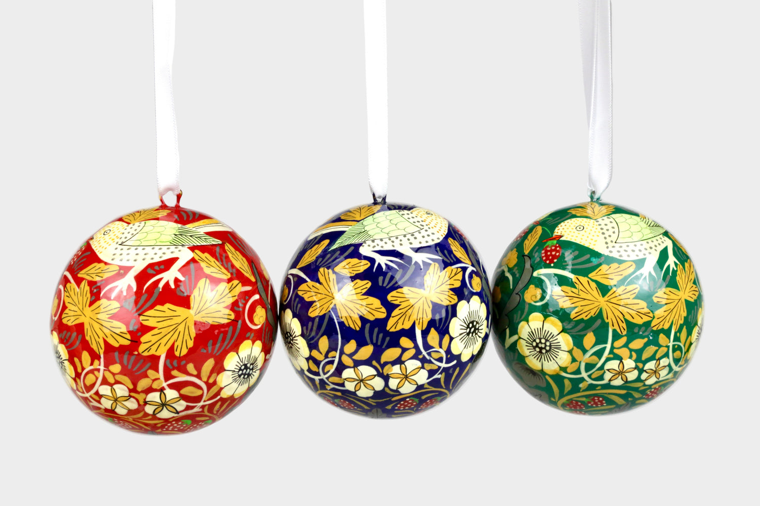 Three decorative Christmas balls with floral patterns on a gray background