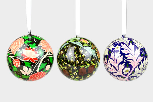 Three decorative spherical ornaments with floral patterns on a light gray background