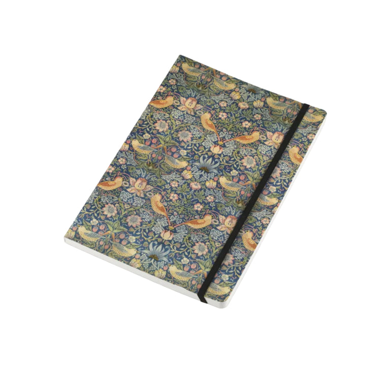 A hardcover notebook with a dense floral and bird pattern in muted blue, green, beige, and yellow tones, secured with a black elastic band, shown on a light gray background.