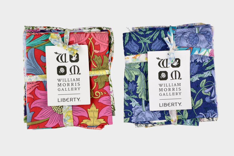 Two folded fabric swatches with colorful patterns and William Morris Gallery tags on a light gray background.