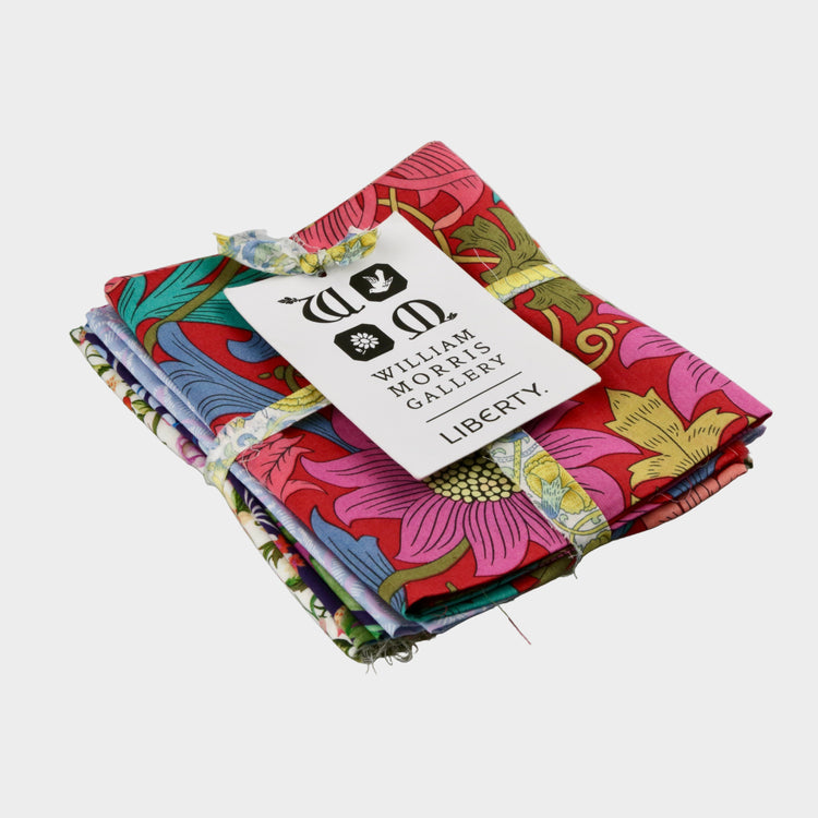 Stack of colorful fabric swatches with a William Morris Gallery label on a gray background