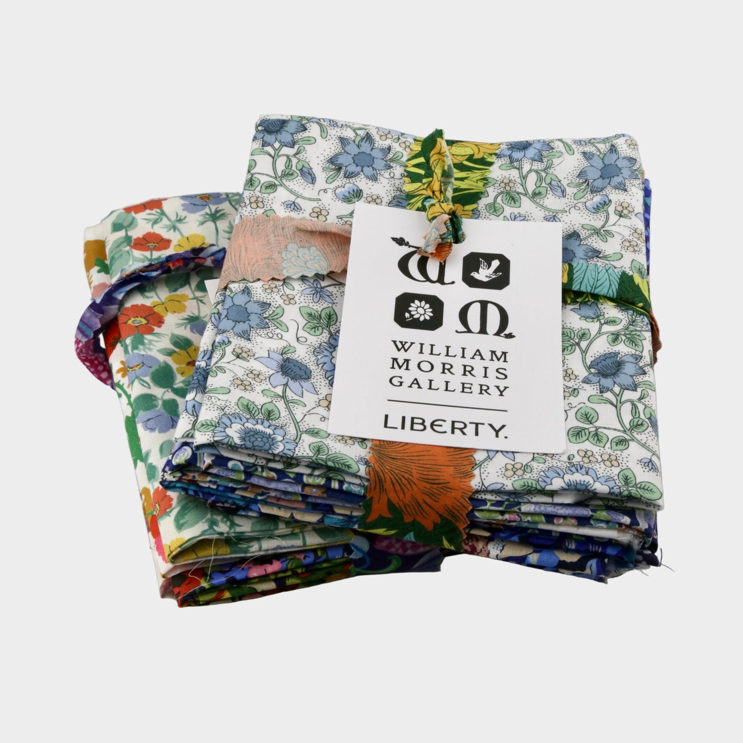 Stack of colorful fabric swatches with a William Morris Gallery Liberty label on a gray background