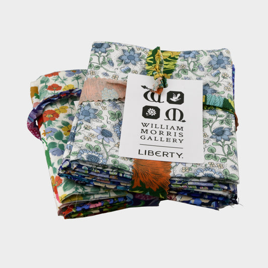 Stack of colorful fabric swatches with a William Morris Gallery Liberty label on a gray background
