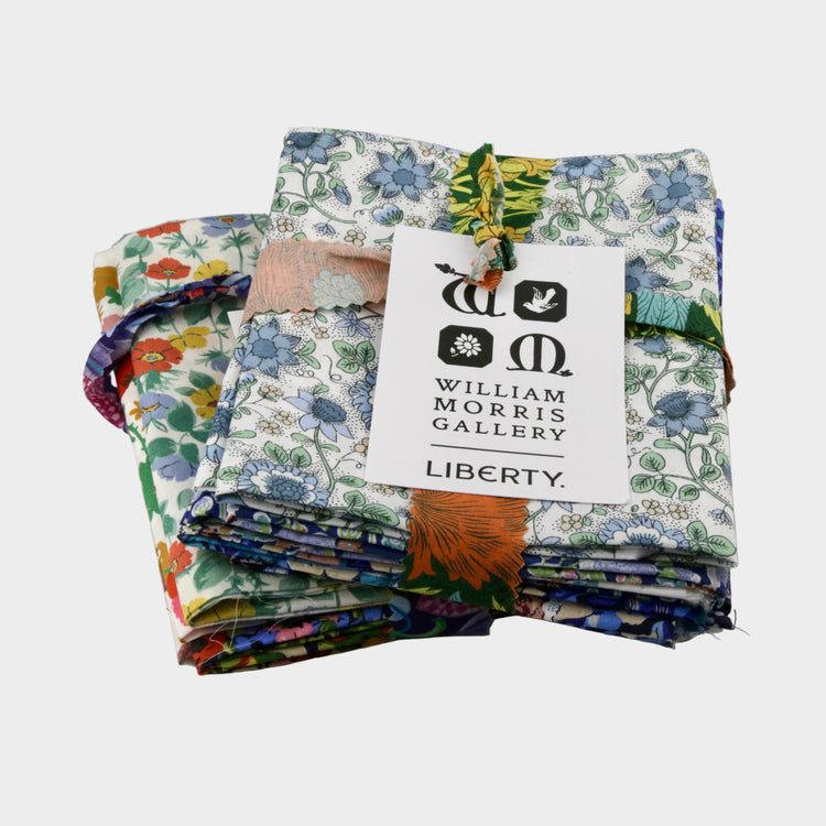 Stack of colorful fabric swatches with a William Morris Gallery Liberty label on a gray background