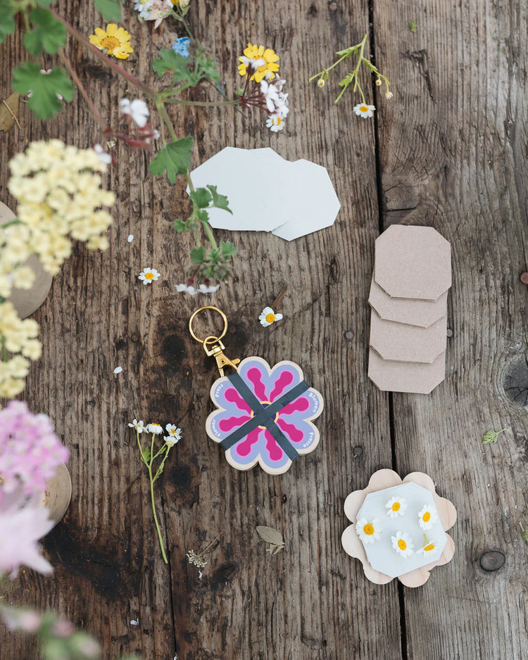 Floral keychain and stickers on a wooden surface with flowers around