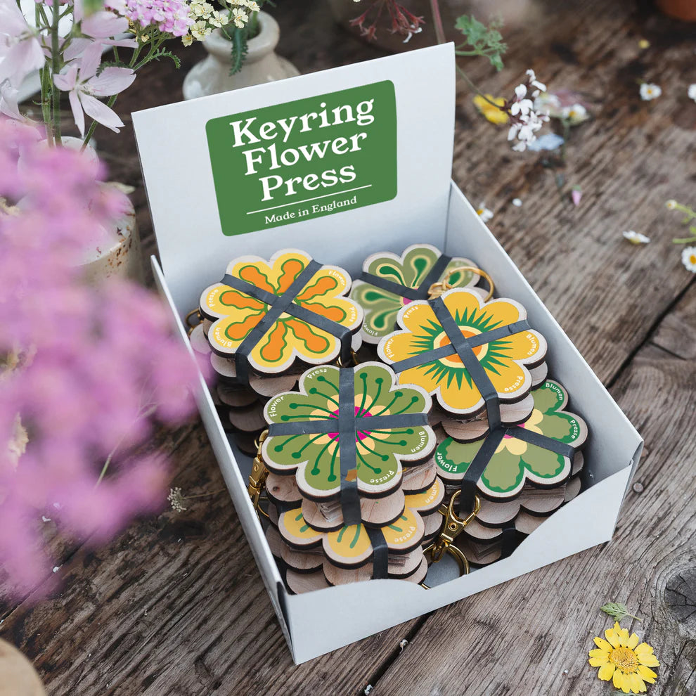 Keyring Flower Press packaging with floral designs on a wooden surface