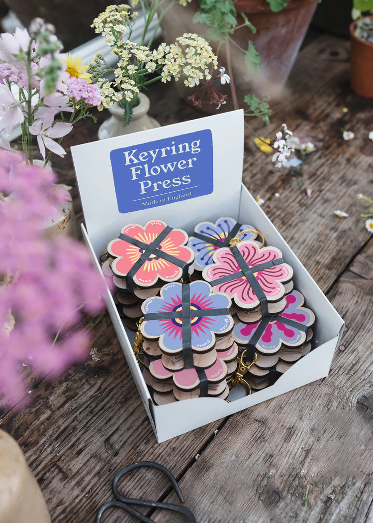 Keyring flower press packaging on a wooden surface with flowers around