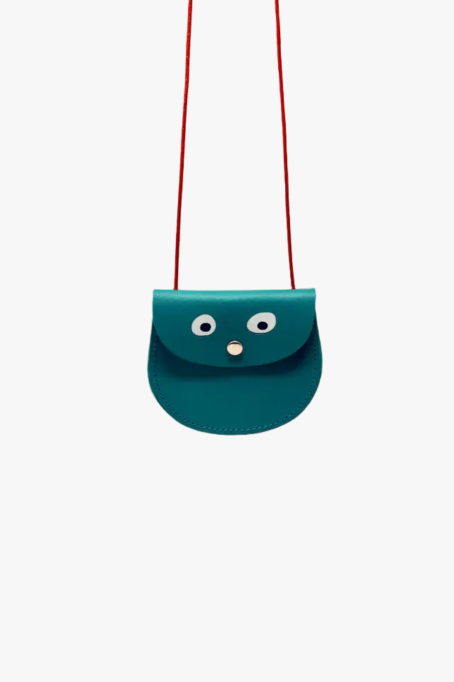Teal handbag with a face design on a pink background