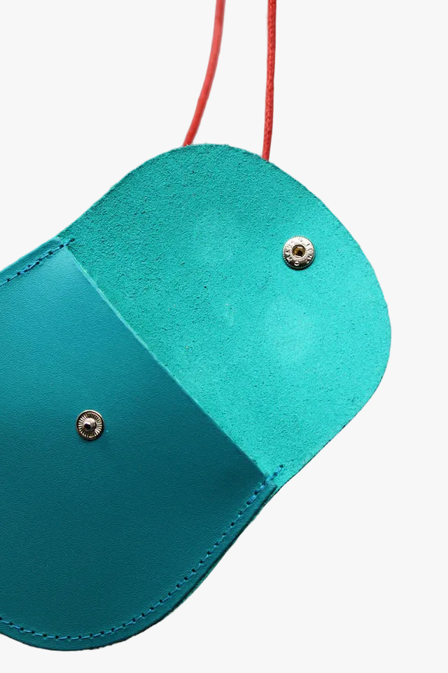 Teal pouch with silver buttons on a pink background