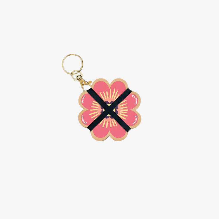 Floral keychain with a pink flower design on a beige background