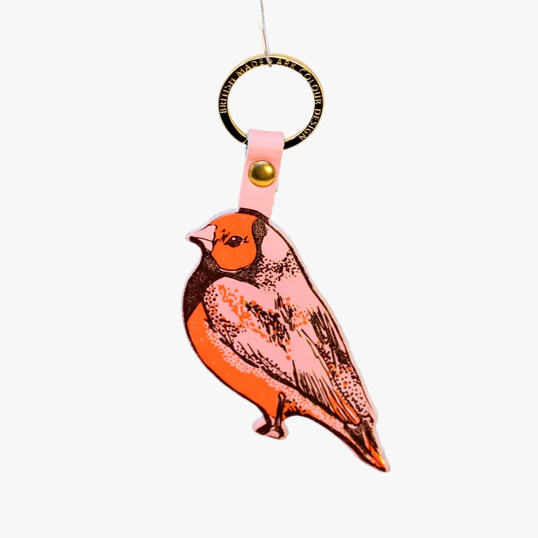 Bird-shaped keychain with pink strap on an orange background