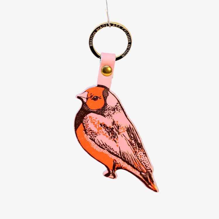 Bird-shaped keychain with pink strap on an orange background
