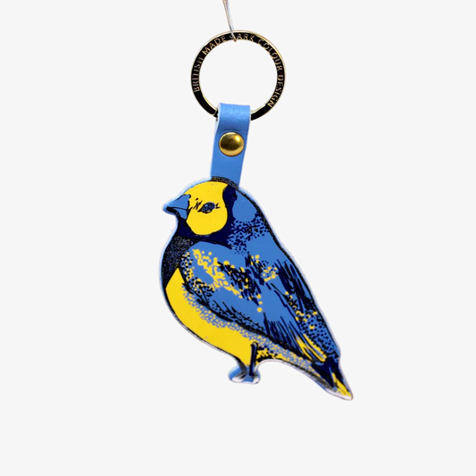 Bird-shaped keychain with blue and yellow design on a brown background